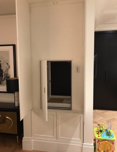 residential dumbwaiter with the white panels and dumbwaiter door open to show the dumbwaiter